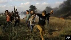 Palestinski demonstranti traže zaklon od suzavca koji su ispalile izraelske snage, dok drugi pale gume u blizini granice Pojasa Gaze i Izraela, tokom protesta istočno od Kan Junisa, u Pojasu Gaze, 1. juna 2018.