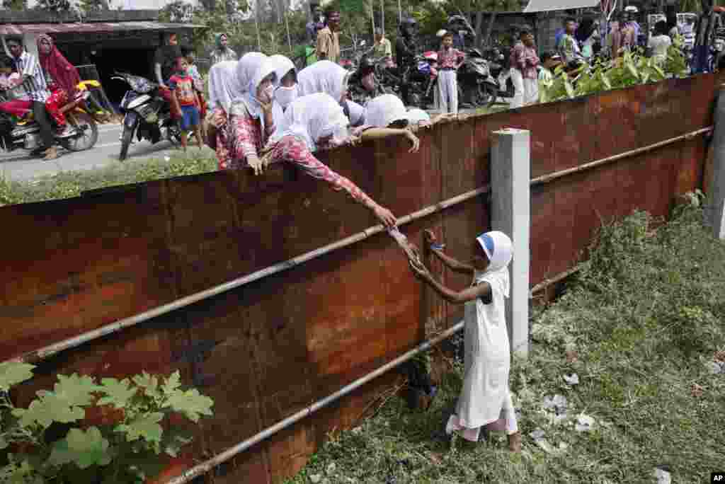 School children hand food to a young Rohingya girl at a temporary shelter in Bayeun, Aceh province, May 21, 2015.