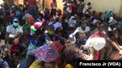 Deslocados, vítimas, da violência armada em Cabo Delgado aguardam na rua com as senhas para adquirir os seus produtos através da ajuda do PMA, em Pemba.
