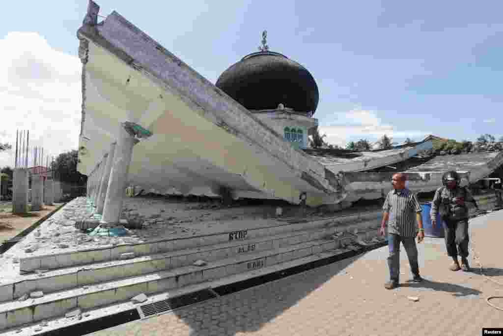 Warga berjalan dekat sebuah masjid yang ambruk akibat gempa di Meuredu, Pidie Jaya, Aceh (7/12). (Reuters/Antara)