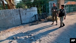 Security forces inspect the scene of a rocket attack at the gate of al-Zawra public park in Baghdad, Iraq, Nov. 18, 2020. Rockets struck Iraq's capital on Tuesday with four landing inside its heavily fortified Green Zone.
