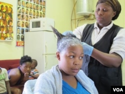Rita Dantaa, who owns a hair salon in downtown Johannesburg, applies relaxer to her client's hair, May 16, 2014 (Gillian Parker for VOA).