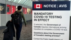 Seorang pelancong berjalan melewati papan pengumuman yang memberitahukan kewajiban untuk menjalani tes COVID-19 yang terpasang di Bandara Internasional Pearson, Toronto, Ontario, Kanada, pada 18 Desember 2021. (Foto: Reuters/Carlo Allegri)