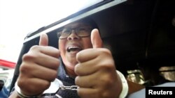 FILE - Detained Reuters journalist Wa Lone gestures to the media as he is escorted by police after a court hearing in Yangon, Myanmar, Apr. 11, 2018.