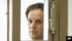 Reporter Wall Street Journal Evan Gershkovich berdiri di balik jeruji kaca di dalam ruang persidangan di gedung pengadilan Kota Moskow, Rusia, pada 22 Juni 2023. (Foto: AP/Dmitry Serebryakov)