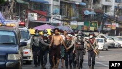 police march with a resident arrested during a crackdown on protesters
