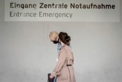Alexei Navalny's wife Yulia, background, arrives at the Charite hospital in Berlin, Germany, Aug. 24, 2020.