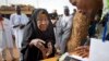 FILE - A Nigerian woman validates her voting card with a fingerprint reader so she can vote later in the day in the town of Daura, March 28, 2015. 