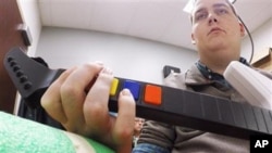 In this March 2016 photo provided by Ohio State University, Ian Burkhart plays a guitar video game as part of a study with neural bypass technology at The Ohio State University Wexner Medical Center in Columbus. 