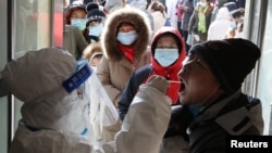 河北省石家庄一名身穿防护服的医护人员在给居民做病毒核酸检测。（2021年1月6日）