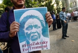 FILE - Iranian and Nigerian students hold posters of Nigerian Shiite cleric Ibrahim El-Zakzaky during a demonstration outside the Nigerian Embassy in Tehran, July 17, 2019.