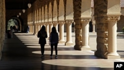 FILE- Students walk on the Stanford University campus in Santa Clara, Calif., March 14, 2019.
