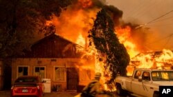 FILE - Fire consumes a home as the Sugar Fire, part of the Beckwourth Complex Fire, tears through Doyle, Calif., July 10, 2021. 