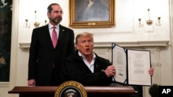 Secretary of Health and Human Services Alex Azar looks on as President Donald Trump shows a spending bill to combat the Coronavirus, at the White House, Friday, March 6, 2020, in Washington. (AP Photo/Evan Vucci)