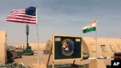 FILE - In this photo taken Apr. 16, 2018, a U.S. and Niger flag are raised side by side at the base camp for air forces and other personnel supporting the construction of Niger Air Base 201 in Agadez, Niger. 