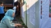 Seorang pemilih memeriksa daftar legislatif yang dipasang di sebuah TPS di Sleman, DIY dalam Pemilu 2019. (Foto: VOA/ Nurhadi)