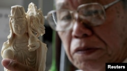 A worker examines ivory carved into the shape of the Chinese Deity Guanyin at a workshop in the southern Chinese city of Guangzhou, October 16, 2009.