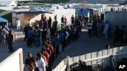 Para migran antri untuk memperoleh bantuan makanan di kamp sementara di Calais, Perancis utara. (AP Photo/Michel Spingler).