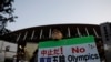 Seorang pengunjuk rasa yang menuntut pembatalan Olimpiade Tokyo 2020 memegang spanduk di depan Stadion Nasional, stadion utama Olimpiade dan Paralimpiade Tokyo 2020. (Foto: Reuters)