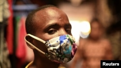 Eugene Amuri, moteki na nzela na wenze ya Kimironko azipi zolo mpe monoko na "kitenge" masque ya liputa mpo na komibatela na coronavirus ya sika (COVID-19), Kigali, Rwanda, 17 mars 2020. REUTERS/Maggie Andresen
