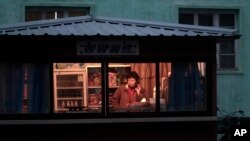 지난해 11월 북한 평양의 한 식료품점 종업원이 휴대전화를 사용하고 있다.