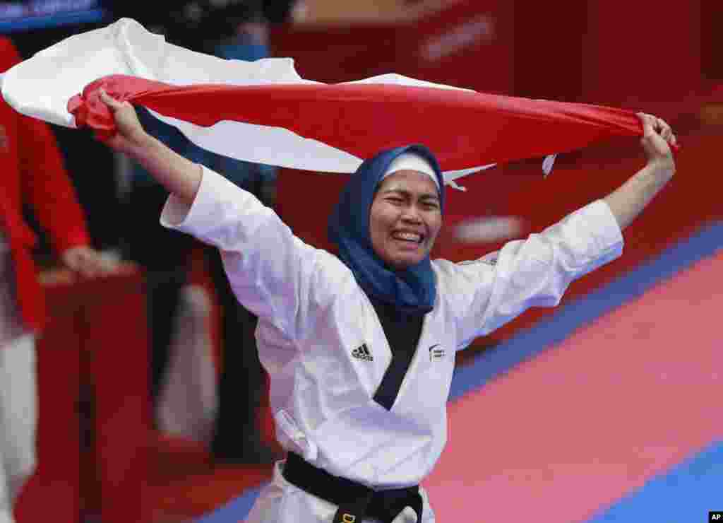 Defia Rosmaniar, merayakan kemenangan dalam final cabang Taekwondo kategori individu poomsae putri pada Asian Games di Jakarta, Minggu 19 Agustus 2018. (AP Photo/Tatan Syuflana)