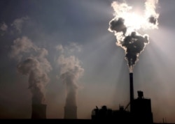 FILE - A coal-burning power plant can be seen behind a factory in China's Inner Mongolia Autonomous Region, October 31, 2010.