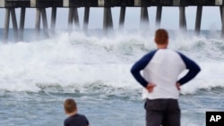 Harrison Westwood, 4, left, and his father Ben watch waves crash near the beach as a subtropical approaches on May 28, 2018, in Pensacola, Fla. 