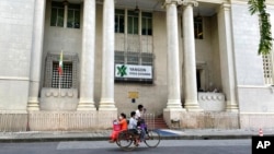 FILE - People onboard a trishaw pass in front of the Yangon stock exchange building in Kyauktada township in Yangon, Myanmar, Nov. 12, 2021. A report released by the World Bank on Jan. 30, 2023, said Myanmar's economy is expected to see growth by the end of September.