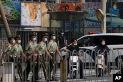 在美國駐北京大使館外守衛的保安看一隊武警走過。（2022年8月3日）