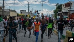 Sejumlah demonstran berlari setelah polisi menembakkan gas air mata untuk membubarkan aksi massa yang menuntut pengunduran diri Perdana Menteri Haiti Ariel Henry di Port-au-Prince, Haiti, pada 10 Oktober 2022. (Foto: AP/Odelyn Joseph)