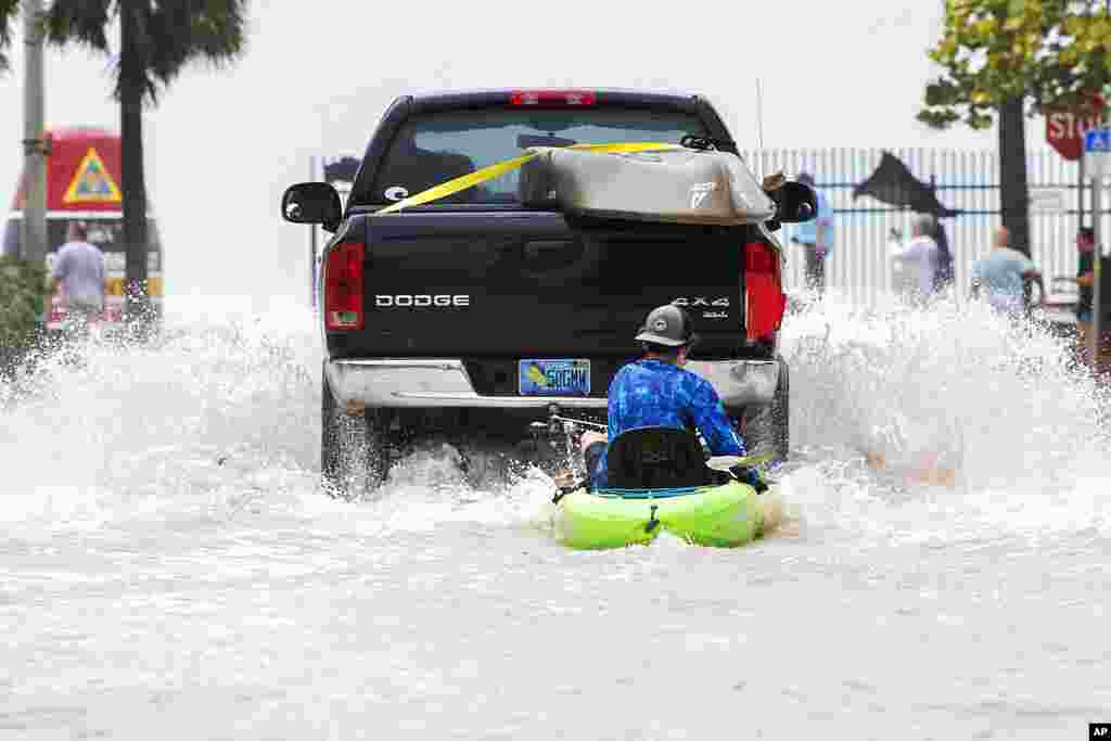 A truck pulls a man on a kayak on a low-lying road after flooding in the aftermath of Hurricane Ian, in Key West, Florida, Sept. 28, 2022.