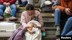 Seorang prempuan dan kucing peliharaannya berlindung di sebuah stasiun kereta bawah tanah di Kyiv menyusul serangan rudal yang dilakukan Rusia di kota tersebut, pada 11 Oktober 2022. (Foto: Reuters/Viacheslav Ratynskyi)