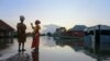 Dua perempuan tampak menunggu datangnya perahu ketika banjir menggenangi jalanan di Wadata, Makurdi, Nigeria, pada 1 Oktober 2022. (Foto: Reuters/Afolabi Sotunde)