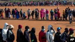 FILE - People affected by the coronavirus economic downturn line up to receive food aid in Pretoria, South Africa, May 20, 2020.
