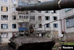 An Ukrainian serviceman sits atop an infantry fighting vehicle, near the bombed-out eastern city of Bakhmut