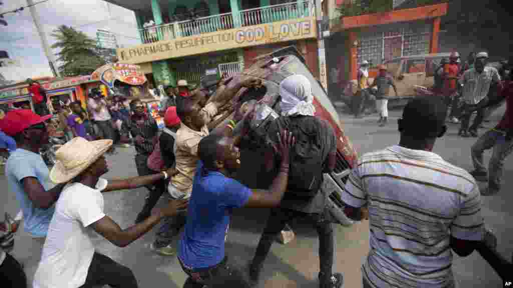 Para demonstran menutup jalan dengan membalikkan mobil selama berlangsungnya protes menuntut pengunduran diri Presiden Michel Martelly di Port - au -Prince, Haiti, 11 Januari 2015 .