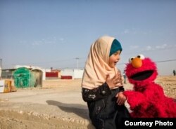 Elmo visits a young girl in a refugee camp. Sesame Workshop, together with the International Rescue Committee, have teamed up in an effort to provide quality education to young children displaced by conflict and persecution. (Photo: courtesy Sesame Workshop)