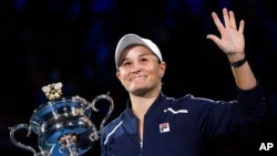Petenis Australia Ashleigh Barty melambaikan tangan seraya memegang trofi Daphne Akhurst Memorial setelah meraih gelar Grand Slam Australia Terbuka 2022 di Melbourne, Australia, pada 29 Januari 2022. (Foto: AP/Andy Brownbill)