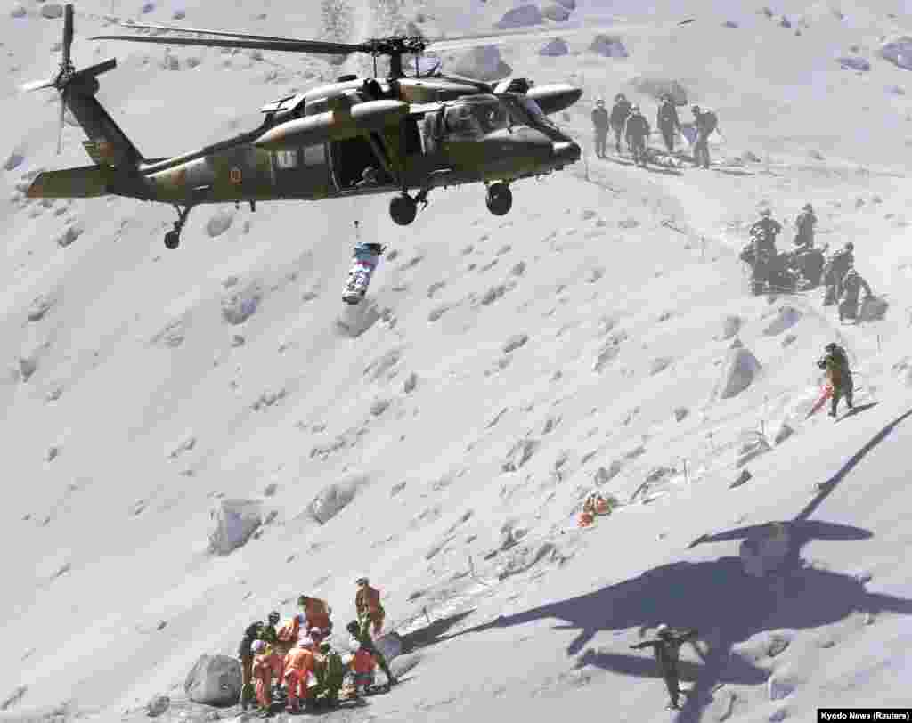A hiker is lifted by a rescue helicopter of Japan Self-Defense Force (JSDF) during a rescue operation at Mount Ontake, which straddles Nagano and Gifu prefectures, central Japan, Sept. 28, 2014.