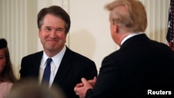 Calon Hakim Agung Mahkamah Agung AS, Hakim Brett Kavanaugh, tersenyum di samping Presiden AS Donald Trump di East Room, Gedung Putih, Washington, 9 Juli 2018.
