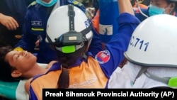 Para petugas SAR membawa korban selamat dari lokasi gedung yang ambruk di Provinsi Preah Sihanouk, Kamboja, 24 Juni 2019. 