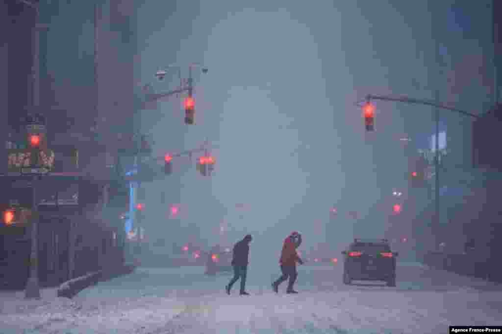Pedestrians and traffic make their way through heavy snow in Times Square, New York, Jan. 29, 2022.&nbsp;&nbsp;A powerful winter storm packing heavy snow and high winds pummeled the U.S. East Coast, forcing the cancellation of thousands of flights as severe weather alerts were sounded across a region of around 70 million people.