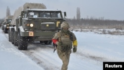 A service member of the Ukrainian Armed Forces runs near self-propelled multiple rocket launcher systems during drills in the Kherson region, Ukraine, in this handout picture released Feb. 1, 2022. (Ukrainian Armed Forces Press Service/Handout via Reuters)