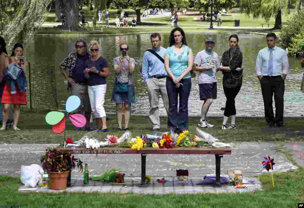 People pause by a bench at Boston's Public Garden, Aug. 12, 2014, where a small memorial has sprung up at the place where Robin Williams filmed a scene during the movie, "Good Will Hunting."
