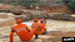Para petugas pemadam kebakaran membantu warga menyebrangi sungai setelah salah satu jembatan di wilayah Itamaraju, di selatan Bahia, Brasil, rusak akibat hujan deras yang melanda pada 12 Desember 2021. (Foto: AFP/Bahia State Fire Department)
