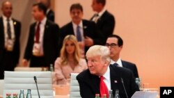 Predsednik Tramp sedi ispred članova američke delegacije, sa ćerkom Ivankom u pozadini, na jednoj od sesija G-20. 