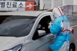 A medical staff member in protective gear prepares to take samples from a visitor at a 'drive-thru' testing center for the novel coronavirus disease of COVID-19 in Yeungnam University Medical Center in Daegu, South Korea, March 3, 2020.