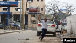 A man raises his hands as he runs from the scene of a suicide bomb attack outside the Hotel Naso-Hablod in Somalia's capital, Mogadishu, June 25, 2016.