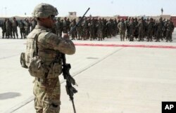 FILE - U.S. military personal stands guard during a graduation ceremony for Afghan troops, in Lashkargah, capital of southern Helmand province, Afghanistan.